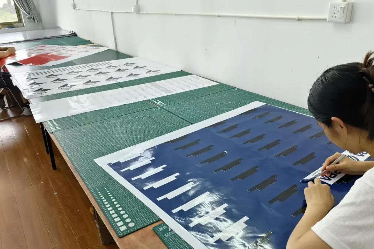 A team member checking printed material on a cutting workbench.