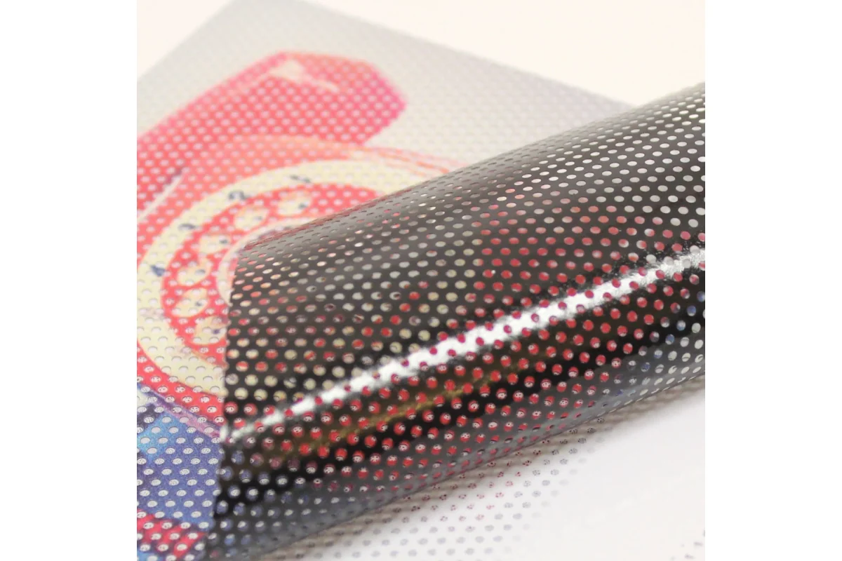 A curved piece of printed perforated window film showing its black reverse side.