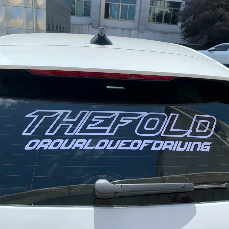 A large outlined lettering decal across the rear window of a white car.