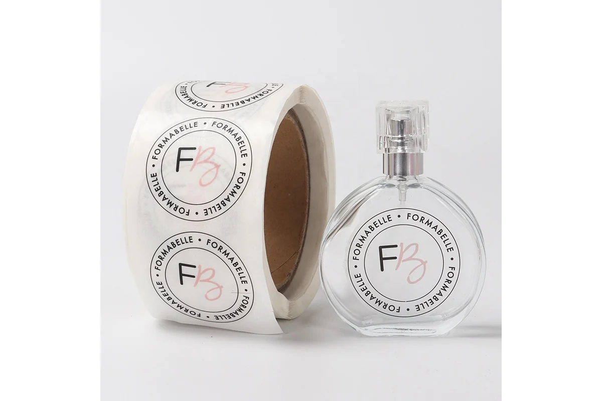 A transparent bottle beside a roll of clear round logo labels