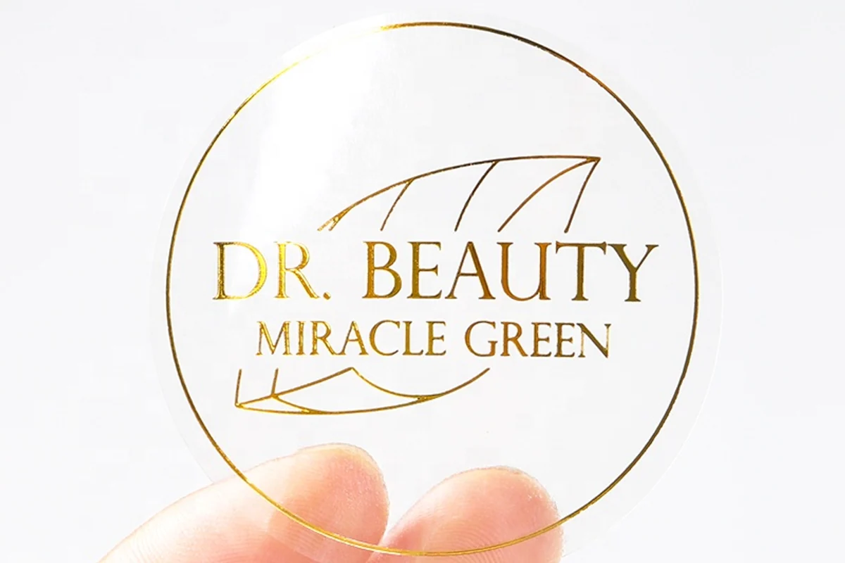 A round transparent label with gold printed lettering