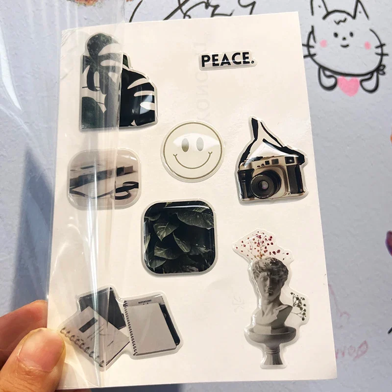 A hand holding a decorative epoxy sticker sheet inside a clear sleeve.