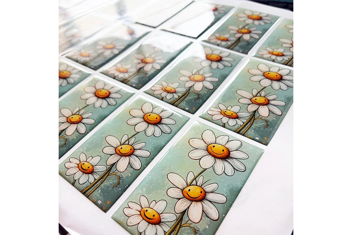 Rectangular epoxy stickers printed with smiling daisy illustrations.