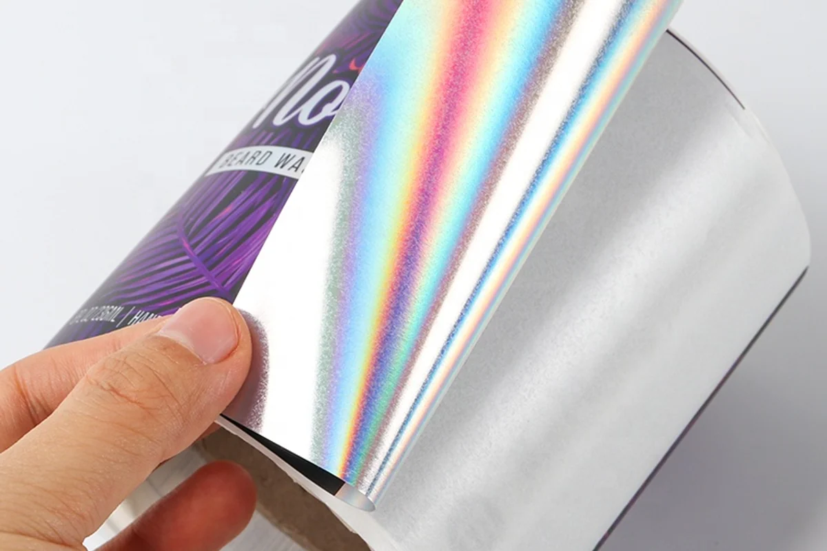 A hand lifting a strip of rainbow-reflective film