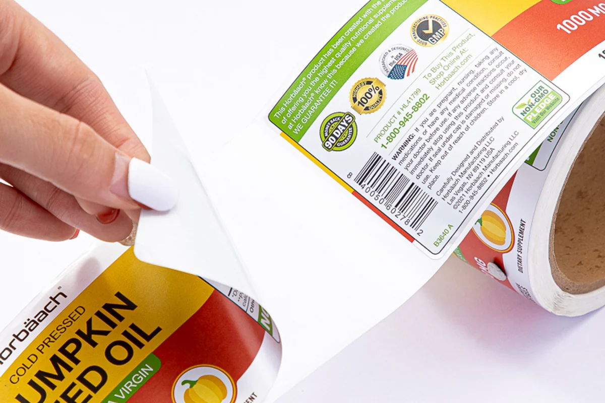 A hand peeling a printed label from its roll backing
