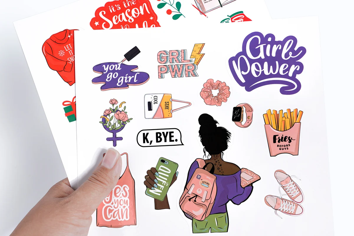Hand holding a printed sheet with lettering and illustrations