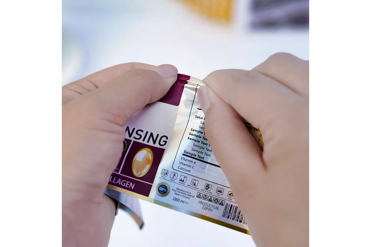 Hands holding a printed label film to show its flexibility.
