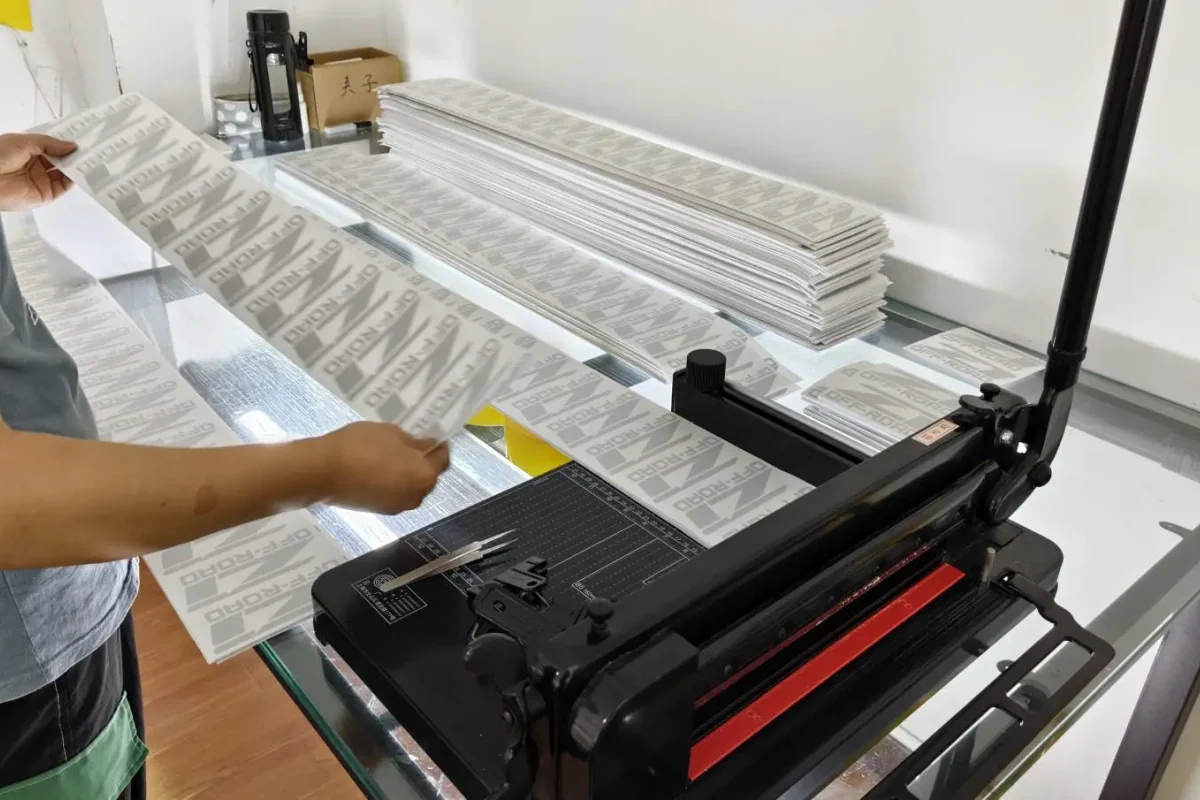 A team member handling printed sheets on a cutting workbench.