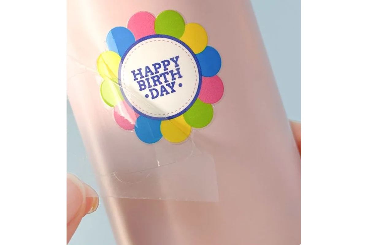 Clear carrier film being lifted from a colorful flower shaped transfer on a pink container.