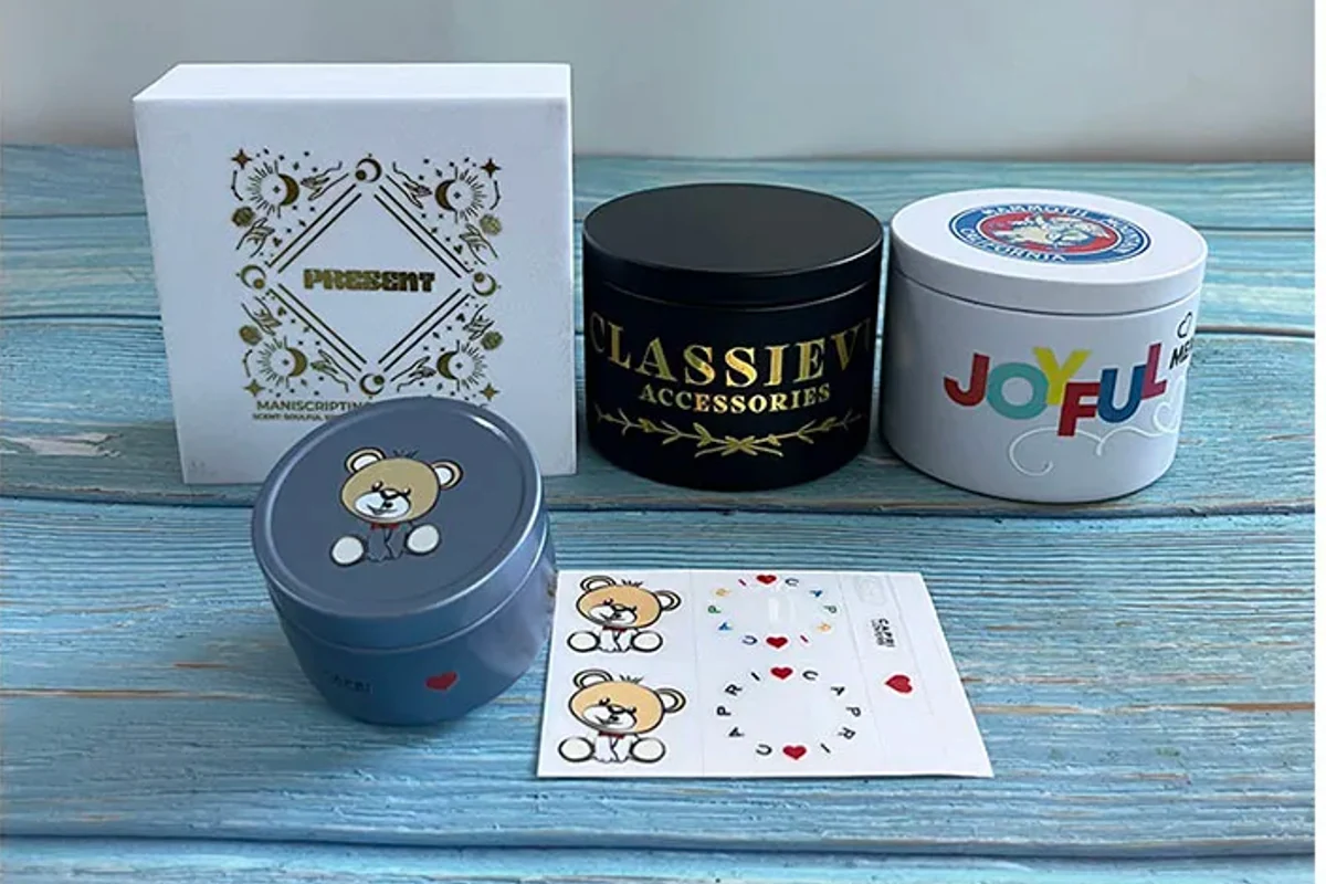 Printed transfer designs and a decorated box beside three finished containers.
