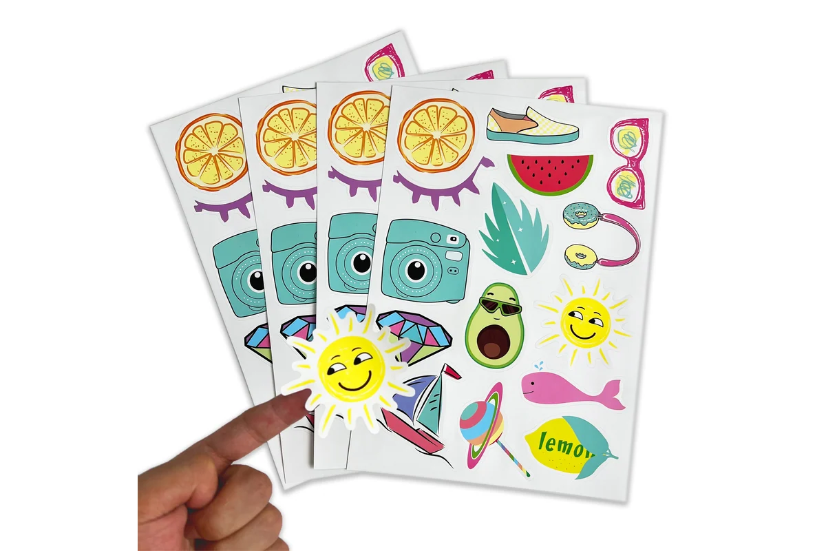 A hand peeling a printed sun sticker from an illustrated sheet.